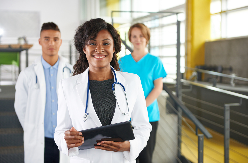 Portrait of a friendly female african american doctor and team in bright modern office Portrait of a friendly female african american doctor and team in bright modern office